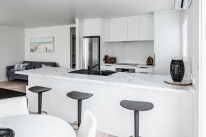 芒格努伊山Awesome Beach House on Oceanview Road的厨房配有白色橱柜和带凳子的台面