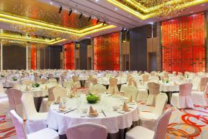 南阳Holiday Inn Nanyang, an IHG Hotel的一个带白色桌椅的大型宴会厅
