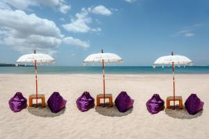 金巴兰Kedonganan Beach Villas的海滩上一群紫色椅子和遮阳伞