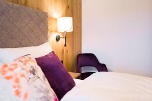 阿尔卑巴赫Boutiquehotel die Alpbacherin的一间卧室配有一张带紫色枕头和灯的床。