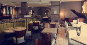 格陵诺克唐提酒店的一间带桌椅和钢琴的餐厅