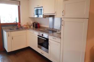 QuartenFerienwohnung Resort Walensee 98 - Seehöckli的厨房配有白色橱柜、水槽和冰箱。