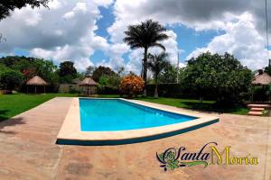 HomúnHotel Santa María Homun的棕榈树庭院中的游泳池