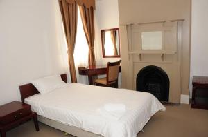 KandosRailway Bistro - Kandos的卧室配有白色的床和壁炉