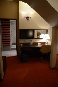 罗兹Agat Hotel的酒店客房配有书桌、电视和椅子