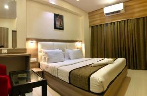孟买Hotel Avon Ruby Dadar的酒店客房设有一张大床和一张桌子。