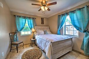 俄克拉何马城Oklahoma City Home with Yard - 5 Mi to Downtown!的一间卧室配有一张带蓝色窗帘的床和吊扇