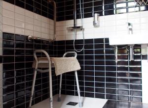 BedousHôtel spa Transhumance & cie的浴室铺有黑色瓷砖,配有椅子和淋浴