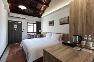 马公貝富門旅館 - 澎湖灣行旅的卧室配有一张白色大床和一张书桌