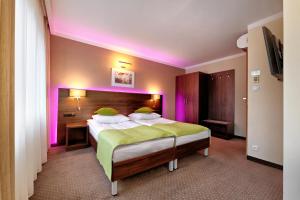 比亚韦斯托克莱斯尼酒店的一间卧室配有一张紫色照明的大床
