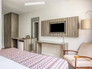 贝洛奥里藏特CHA Pampulha Design Hotel的一间卧室配有一张床、一台电视和一把椅子