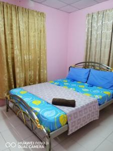 峇株巴辖LAYLA INN的一间卧室配有一张带蓝色枕头和窗帘的床