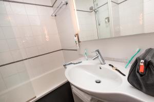 巴黎巴黎马塞纳奥林匹兹宜必思尚品酒店的浴室配有盥洗盆、镜子和浴缸