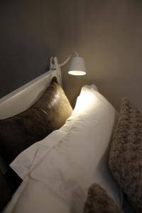 拉马德莱娜新西室酒店的一张带两个枕头的床和墙上的一盏灯