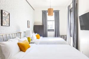 旧金山Sonder Hayes Valley的酒店的客房内设有两张白色的床,配有黄色枕头
