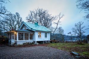 卢恩斯基尔Cottage - Majviken的一座白色的小房子,设有绿色屋顶