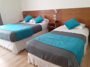 利纳雷斯Hotel Real的两张位于酒店客房的床,配有蓝色枕头