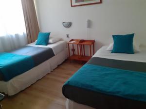 利纳雷斯Hotel Real的客房配有两张带蓝色枕头的床和一张桌子