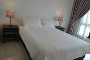 莎阿南Lodge Alpha LaVista at Emira Residence Shah Alam的一间卧室配有一张白色床、两个床头柜和两盏灯。