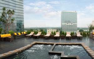 胡志明市Silverland Sakyo Hotel的一座带椅子的屋顶露台和一座位于大楼内的游泳池