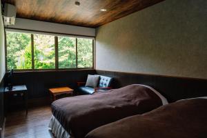 竹田赤川温泉スパージュ-Spaju的卧室配有床、椅子和窗户。