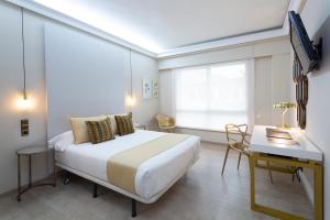 维戈维戈城市酒店的一间卧室配有一张床、一张书桌和一个窗户。