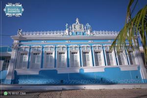 帕尔梅拉斯Pousada Encantos de Palmeiras的蓝白色的建筑,前面有棕榈树