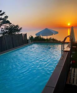 阿纳卡普里帕拉迪索卡普里住宿加早餐旅馆的一个带遮阳伞的游泳池,享有日落美景