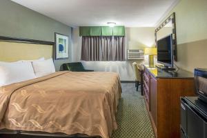 威利斯顿Roosevelt Hotel的配有一张床和一台平面电视的酒店客房