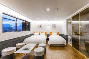 釜山Browndot Hotel Sasang Renecite的酒店客房设有两张床和一张桌子。