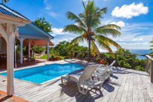 拉特里尼泰Villa Vue Sauvage的一个带游泳池、椅子和棕榈树的甲板
