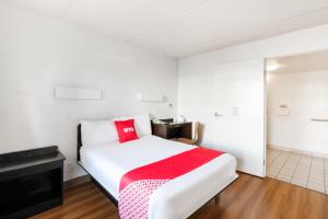 休斯顿OYO Hotel Houston Katy Freeway的卧室配有一张带红色毯子的白色床