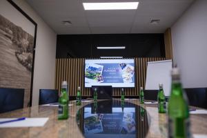RóżanHotel Avangarda的一间会议室,配有桌子和投影屏幕