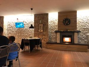 罗卡拉索Villaggio dello sciatore residence paradiso的带壁炉的用餐室,客人坐在桌子旁