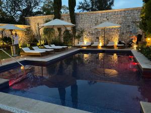 莫雷利亚Hotel Morelia Boutique Villa Italia的庭院内带椅子和遮阳伞的游泳池