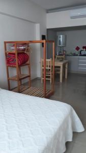 圣米格尔·德·图库玛relajado monoambiente的一间卧室配有一张床铺和一张桌子,还设有一间厨房