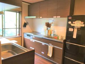 箱根K's House Hostels - Hakone Yumoto Onsen的厨房配有水槽和黑冰箱。