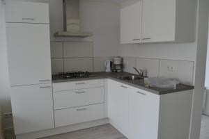 迪斯胡克Vakantiewoning aan duinen en zee in Dishoek的白色的厨房配有白色橱柜和水槽