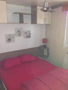 圣特罗佩Mobilhome sur camping le kontiki **** ramatuelle的一间卧室配有一张红色的床和吊扇