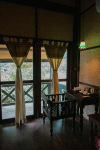 Nongkhiaw农基亚河滨酒店的客房设有桌子和2个带窗帘的窗户。