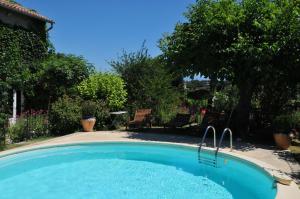奥朗日Chambres d'Hôtes et Gîtes Le Mas Mellou的庭院内的游泳池,带椅子和树木