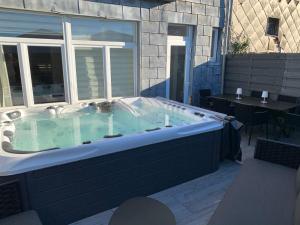 韦尔维耶Maison avec Jacuzzi 5ch的庭院内的按摩浴缸,配有桌子