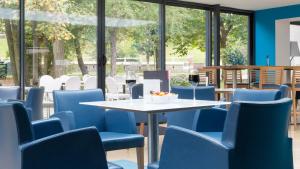 勒图凯-巴黎普拉日勒图凯假日酒店度假村的一间配备有蓝色椅子和桌子的用餐室