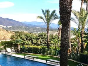 卡萨雷斯Garden Apartment in Finca Cortesin, Altos de Cortesin的棕榈树和山脉环绕的游泳池