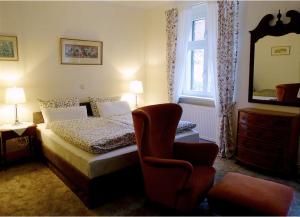 ReitweinPension Gräfliche Villa的一间卧室配有一张床、一把椅子和镜子
