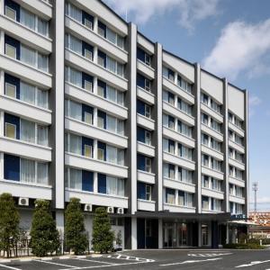 多贺城市Smile Hotel Sendai Tagajyo的前面有树木的白色大建筑