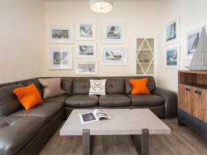 索尔科姆Coxswains Watch的客厅配有棕色沙发和橙色枕头