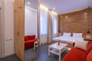 第比利斯5 STAR APART HOTEL的酒店客房,配有一张床和一张红色的沙发