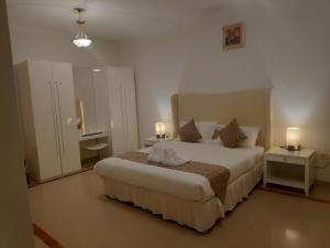 马斯喀特马斯喀特绿洲住处酒店的一间卧室配有一张大床、两张桌子和两盏灯。