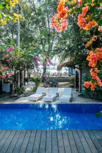 吉利特拉旺安Bale Sampan Boutique Bungalows的一座带椅子和树木及鲜花的游泳池